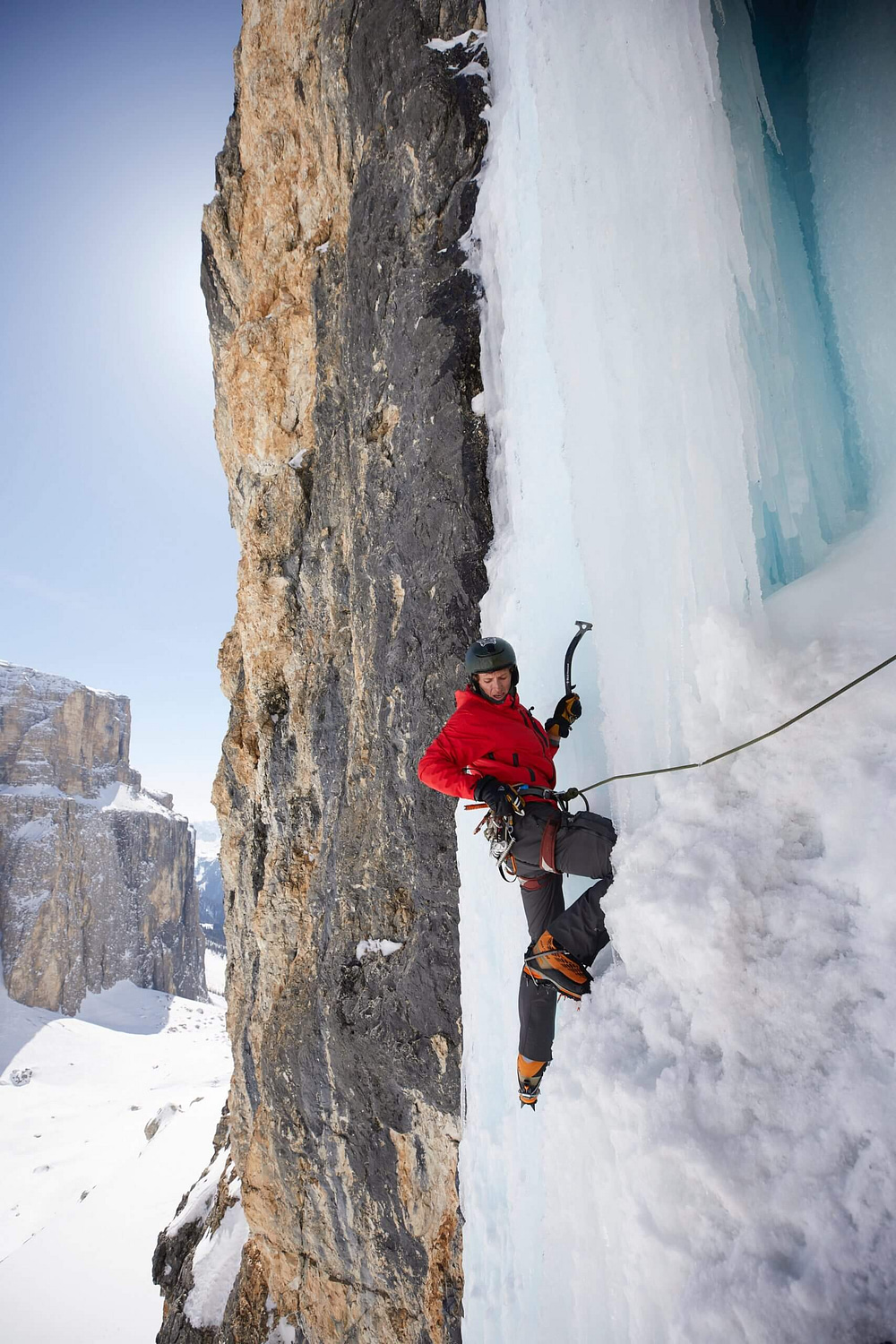 a mountain climber traverses a vertical wall of ice