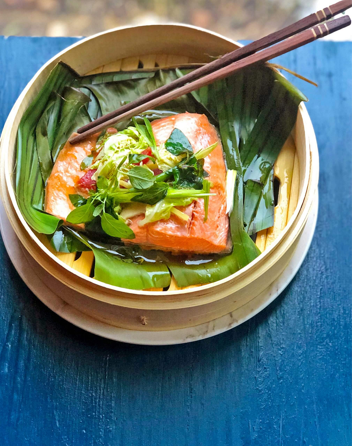 a bamboo steamer filled with salmon and vegetables