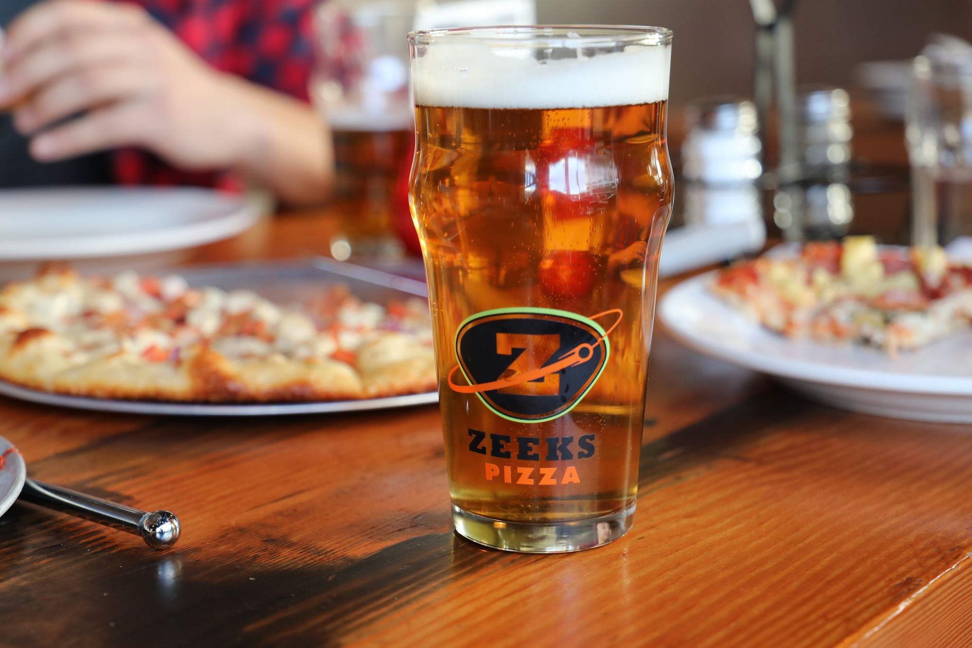 A full glass of tasty looking beer served in a Zeeks Pizza pint glass