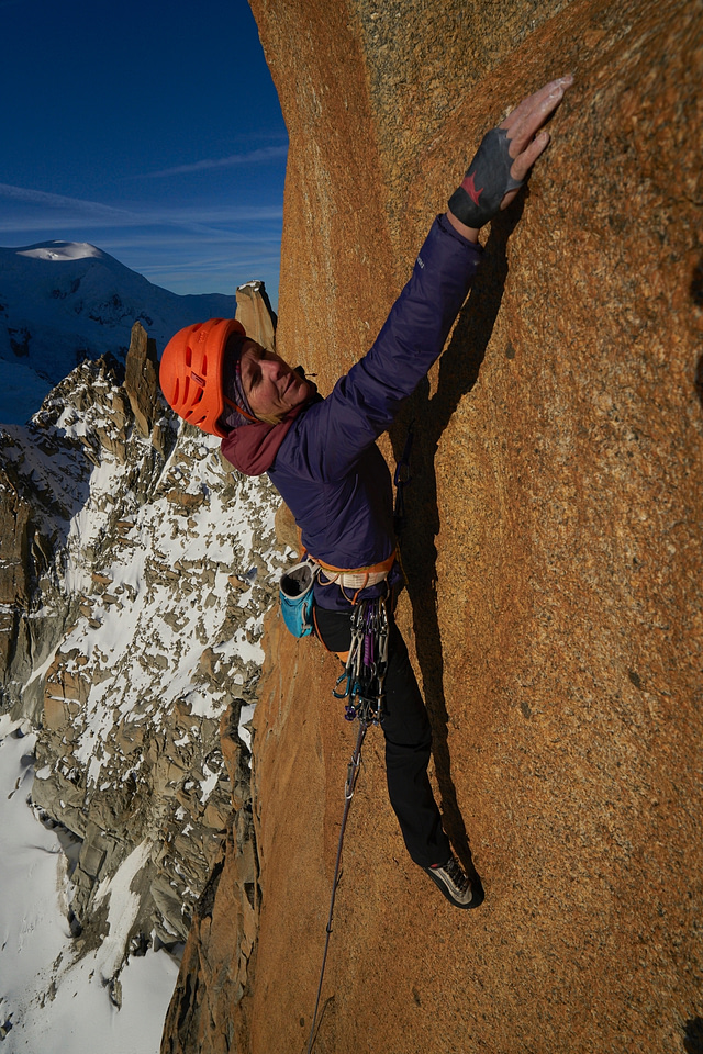 a female rock climber reaches for the next hand hold